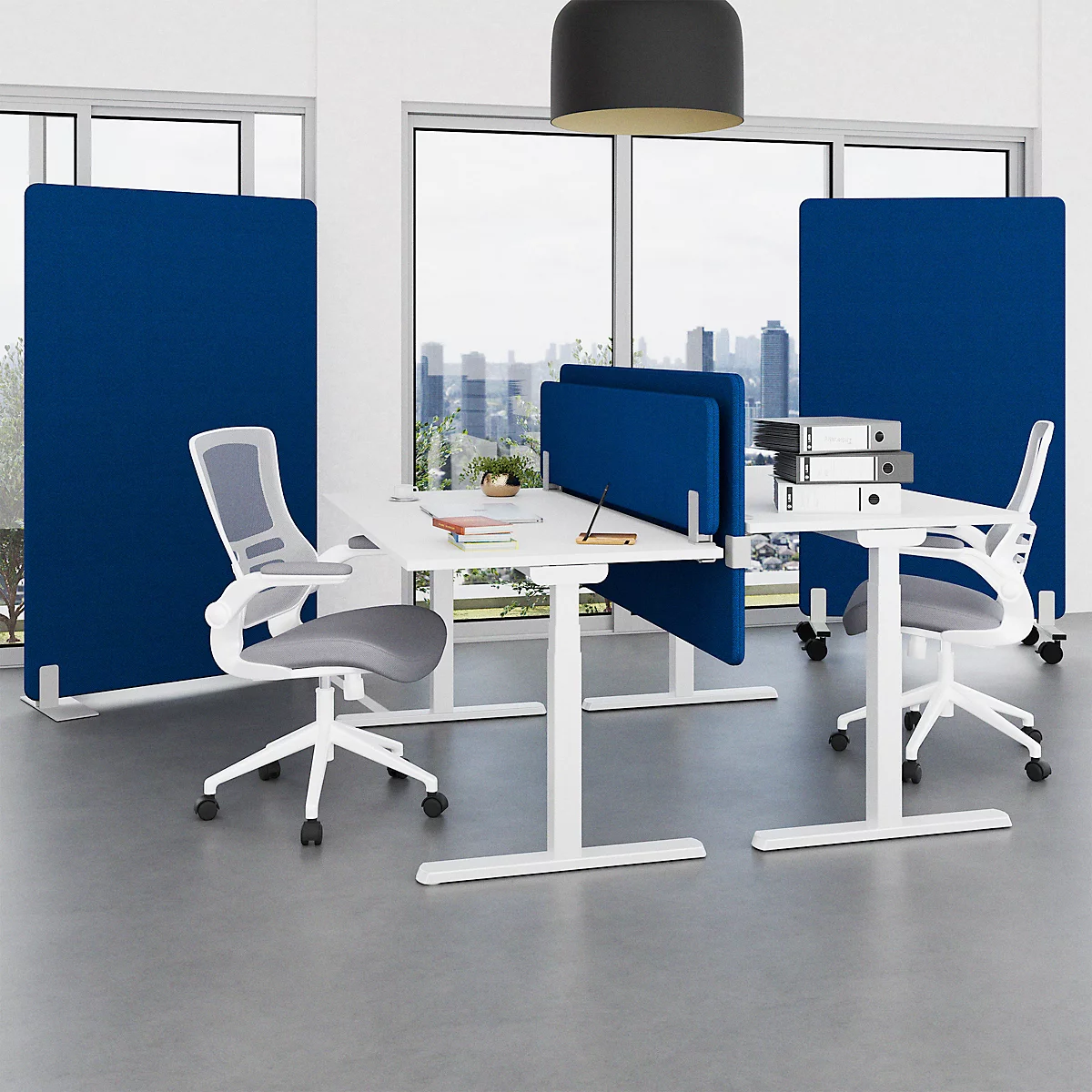 Ein Büro mit zwei Schreibtischen, Stühlen und blauen Trennwänden. Im Hintergrund eine Fensterfront mit Stadtblick.