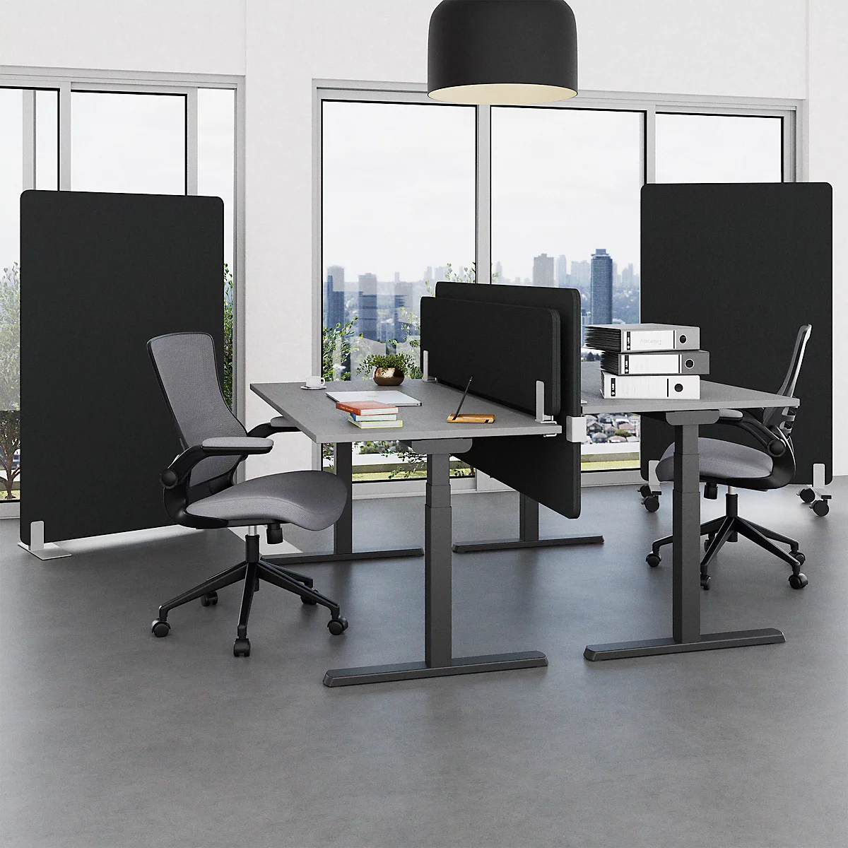 Büro mit höhenverstellbaren Tischen und Trennwänden. Graue Stühle und Aktenordner auf den Tischen.