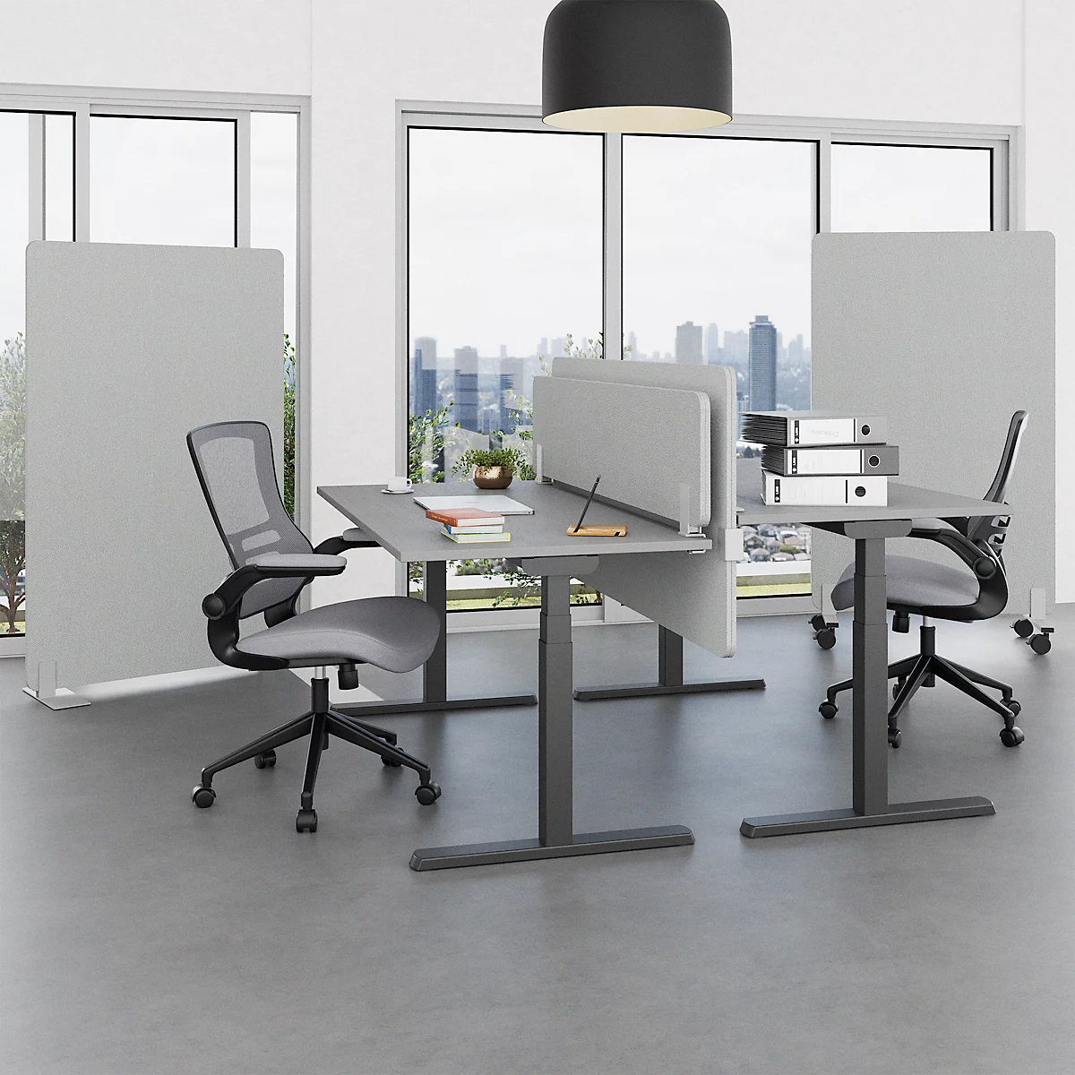 Büro mit Schreibtischen, Stühlen und Trennwänden. Große Fenster bieten Ausblick auf die Skyline. Graue Einrichtung, moderne Arbeitsumgebung.