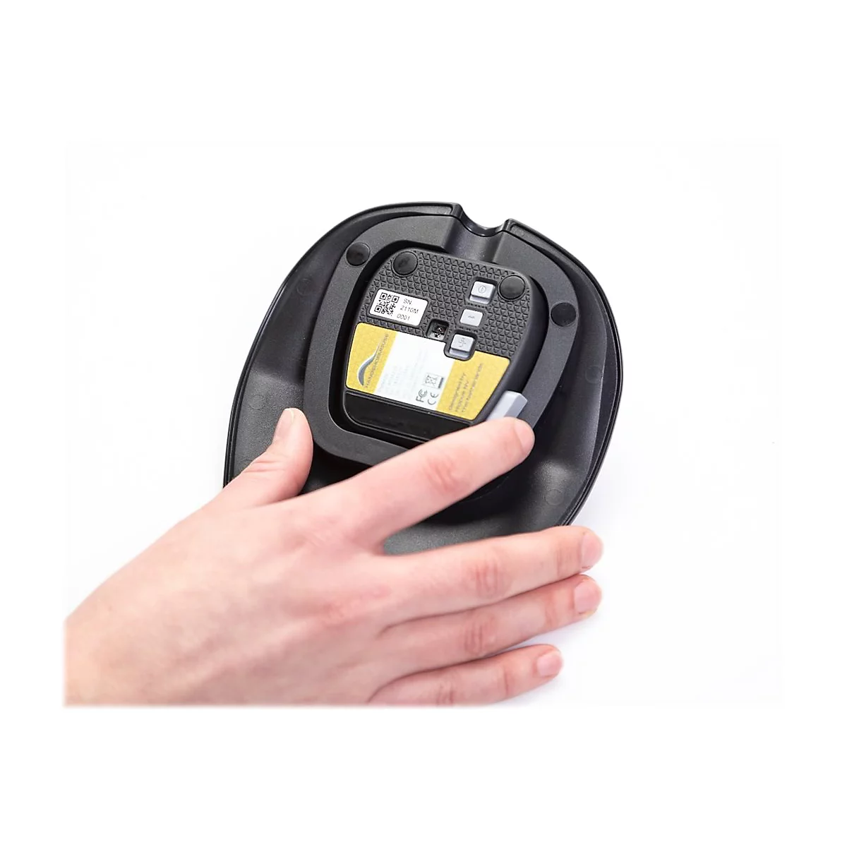 Nahaufnahme: Hand öffnet Batteriefach einer schwarzen Basis mit gelbem Einsatz.