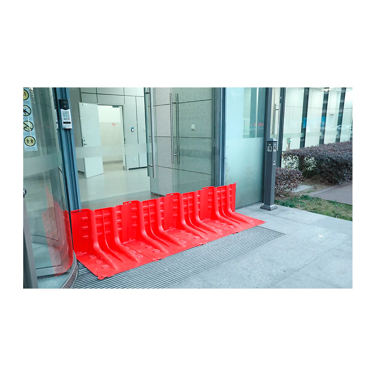 Rote Flutschutzbarriere vor einer Glastür. Schutz vor Überflutung in Gebäuden. Im Hintergrund ein Flur.