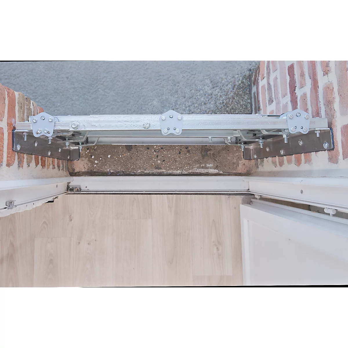 Detailaufnahme einer Türschwelle mit montierter Rampe. Metallkonstruktion, Ziegelwand, Holzfußboden.