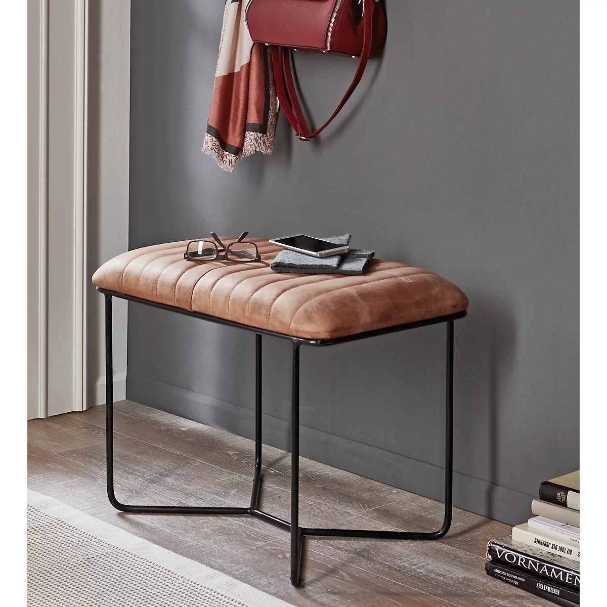 Hocker mit brauner, gesteppter Sitzfläche und schwarzem Metallgestell.