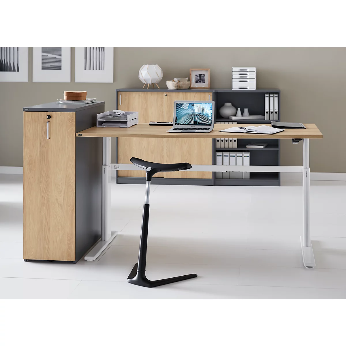 Bureau met in hoogte verstelbaar werkblad, stoel en kastelementen. Laptop en documenten liggen op tafel.