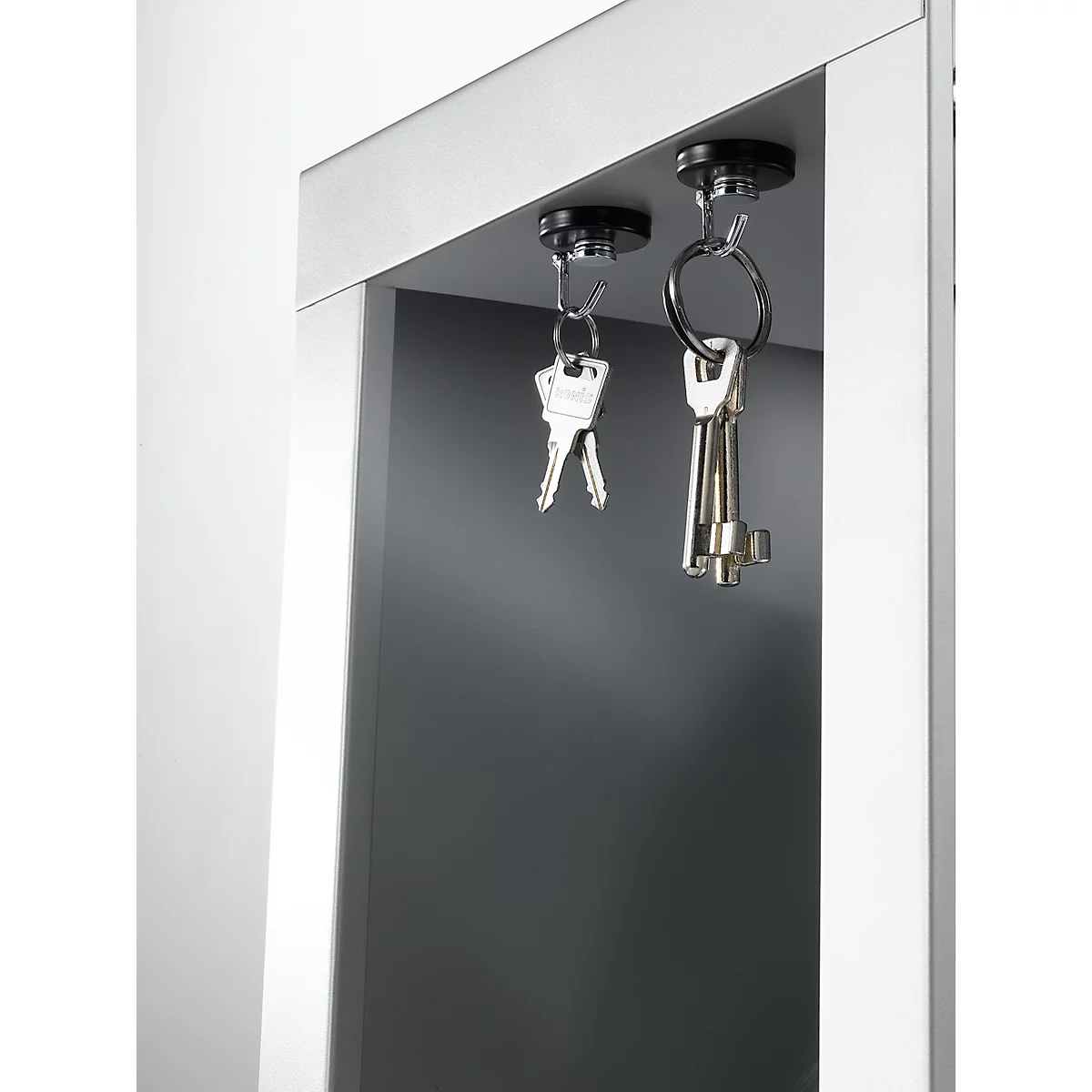 Two keychains hanging from magnets under a gray shelf.
