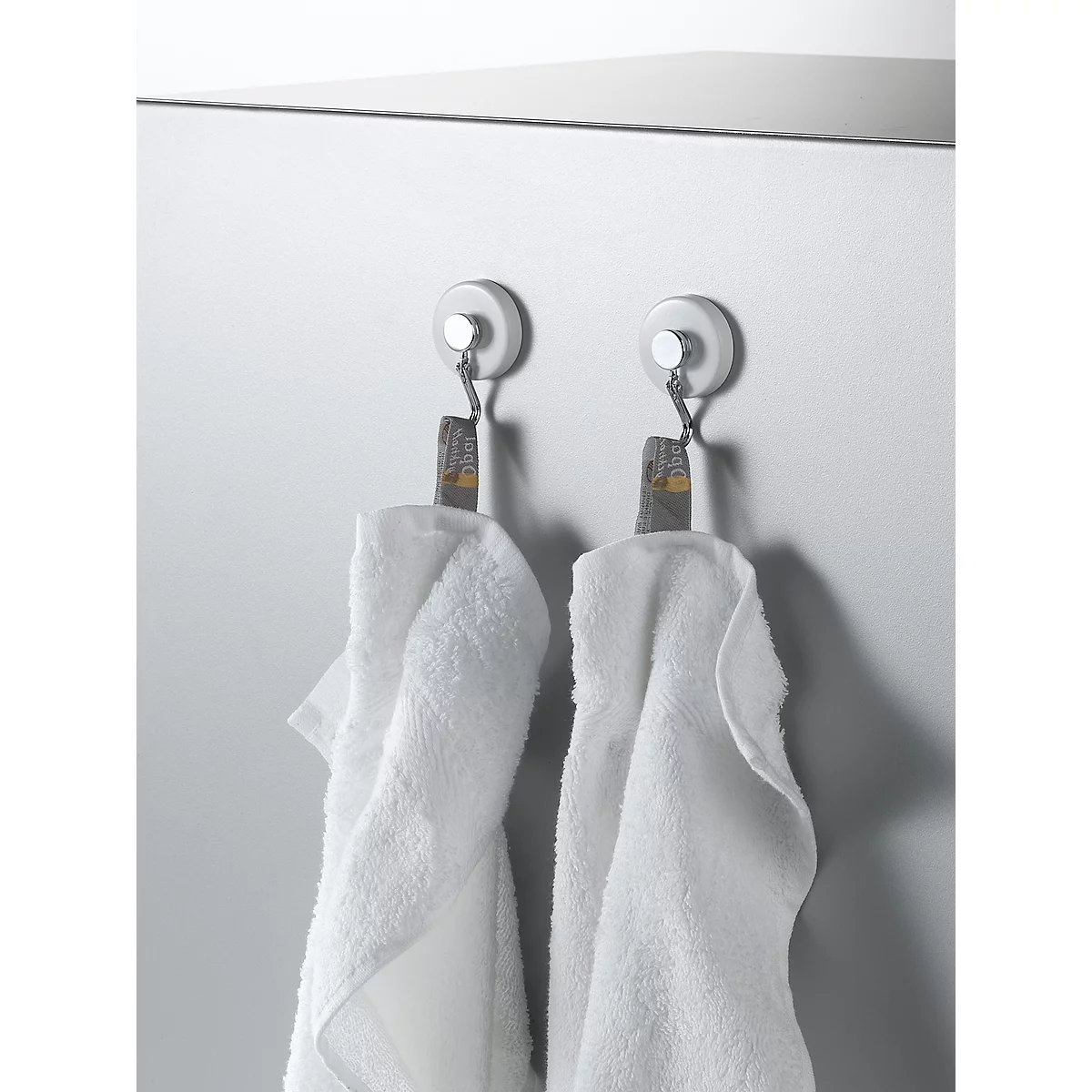 Two white towels hang on hooks. The background is light gray.