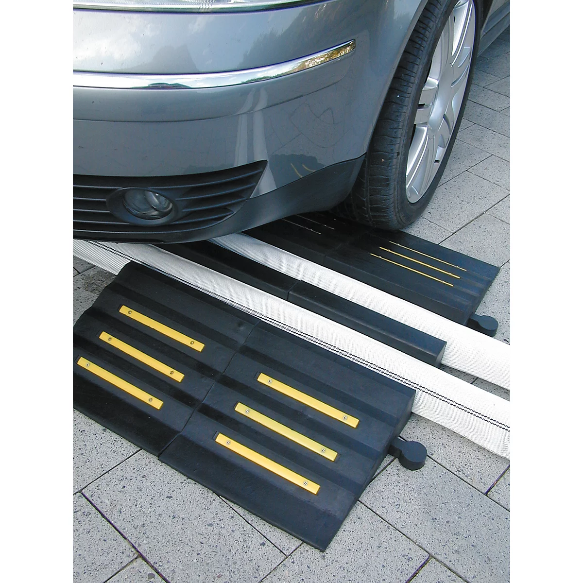 Black car ramp in front of car tire; yellow stripes.
