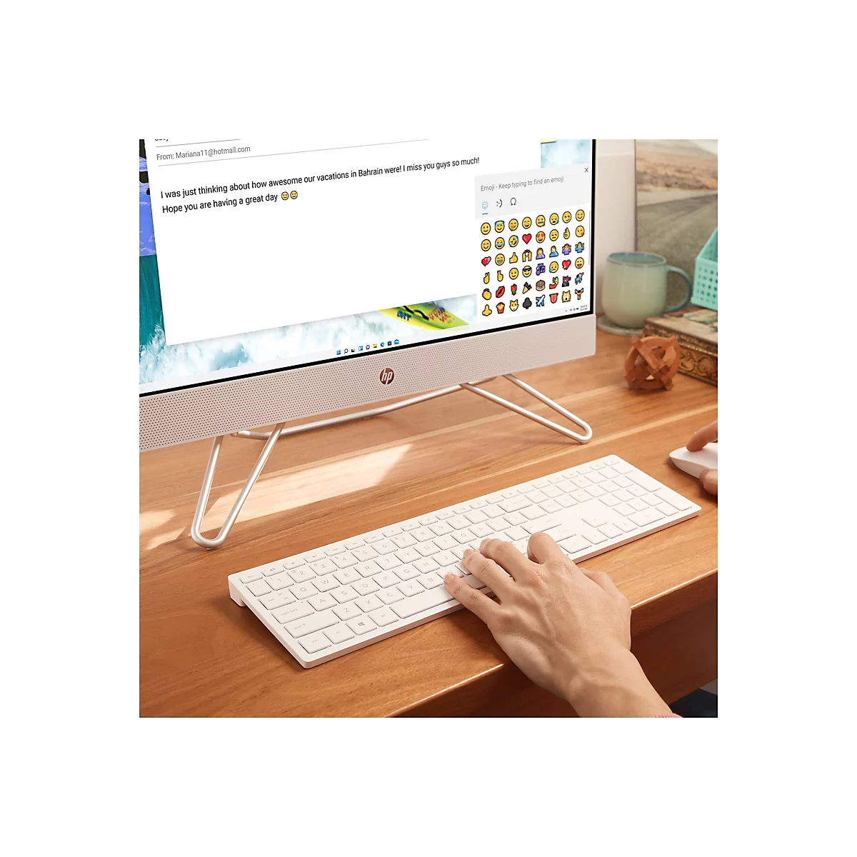 Ein weißer HP-All-in-One-Computer mit angeschlossener Tastatur und Maus steht auf einem Holzschreibtisch. Auf dem Bildschirm wird eine E-Mail angezeigt.