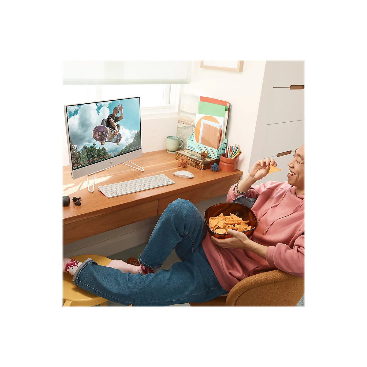 Ein Mann sitzt mit Chips in der Hand vor einem Computer. Auf dem Bildschirm ein Skateboarder.