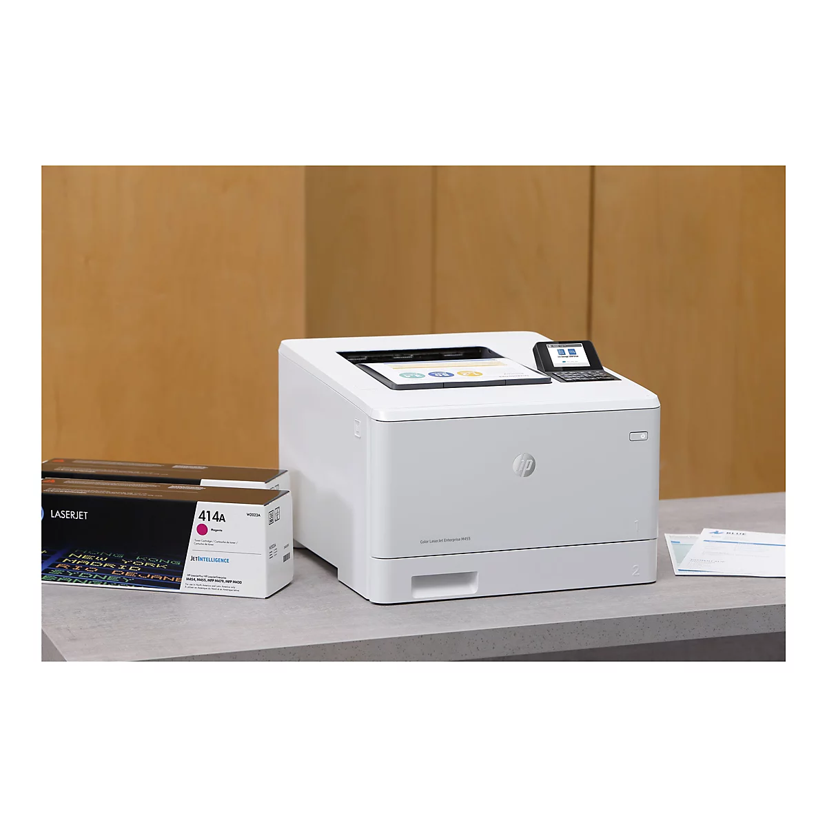 Ein weißer HP Color LaserJet Drucker mit einem Bedienfeld und daneben eine Magenta-Tonerkartusche auf einer grauen Tischplatte.