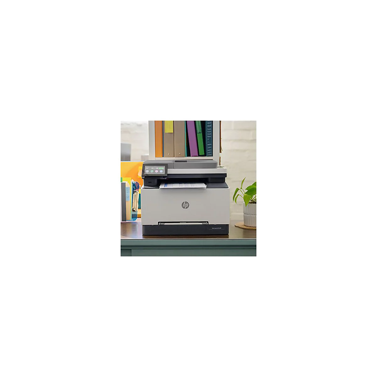Ein HP-Multifunktionsdrucker steht auf einem Schreibtisch. Links Akten, rechts eine Topfpflanze. Auf dem Drucker liegt Papier.