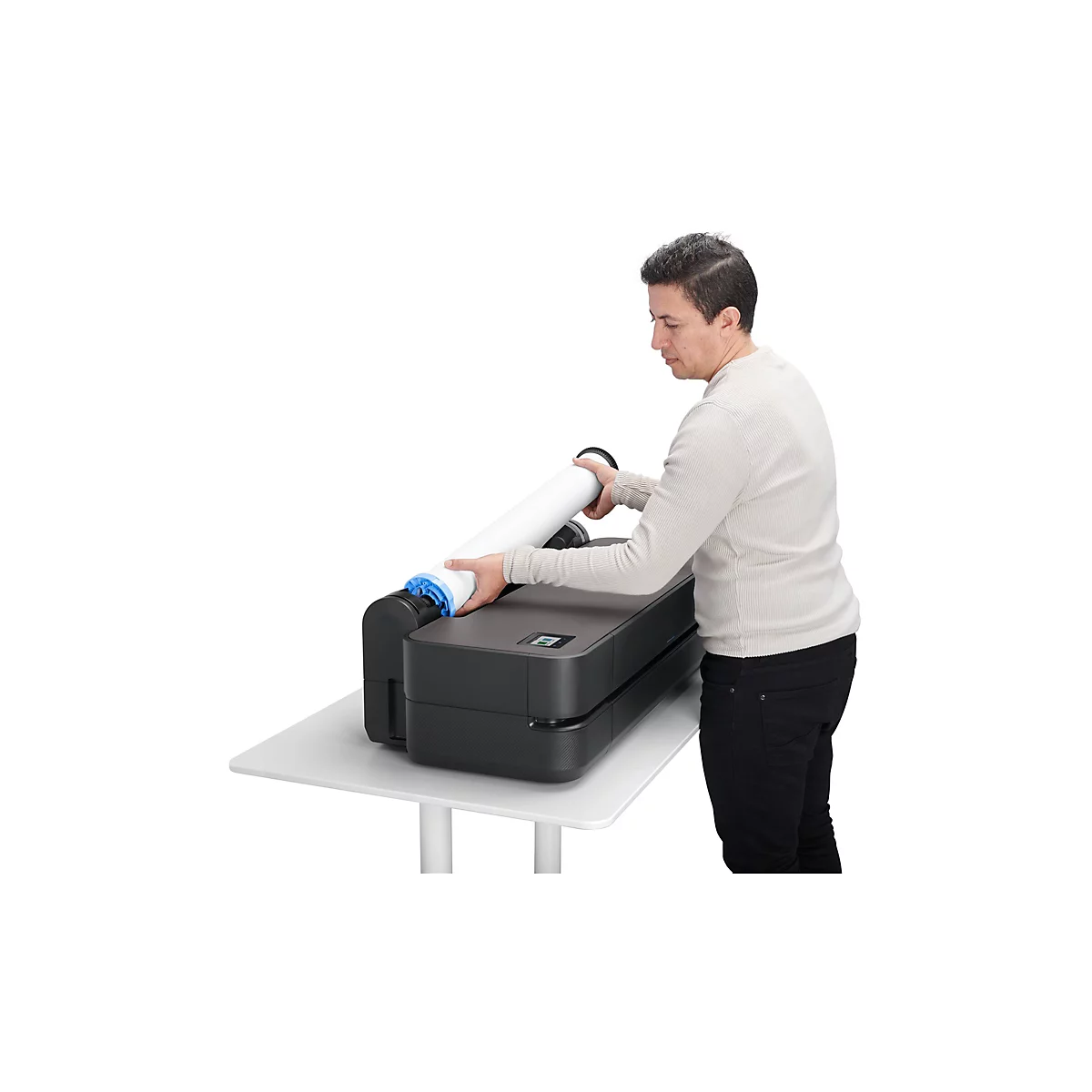 Ein Mann legt eine Rolle Papier in einen Großformatdrucker auf einem weißen Tisch.