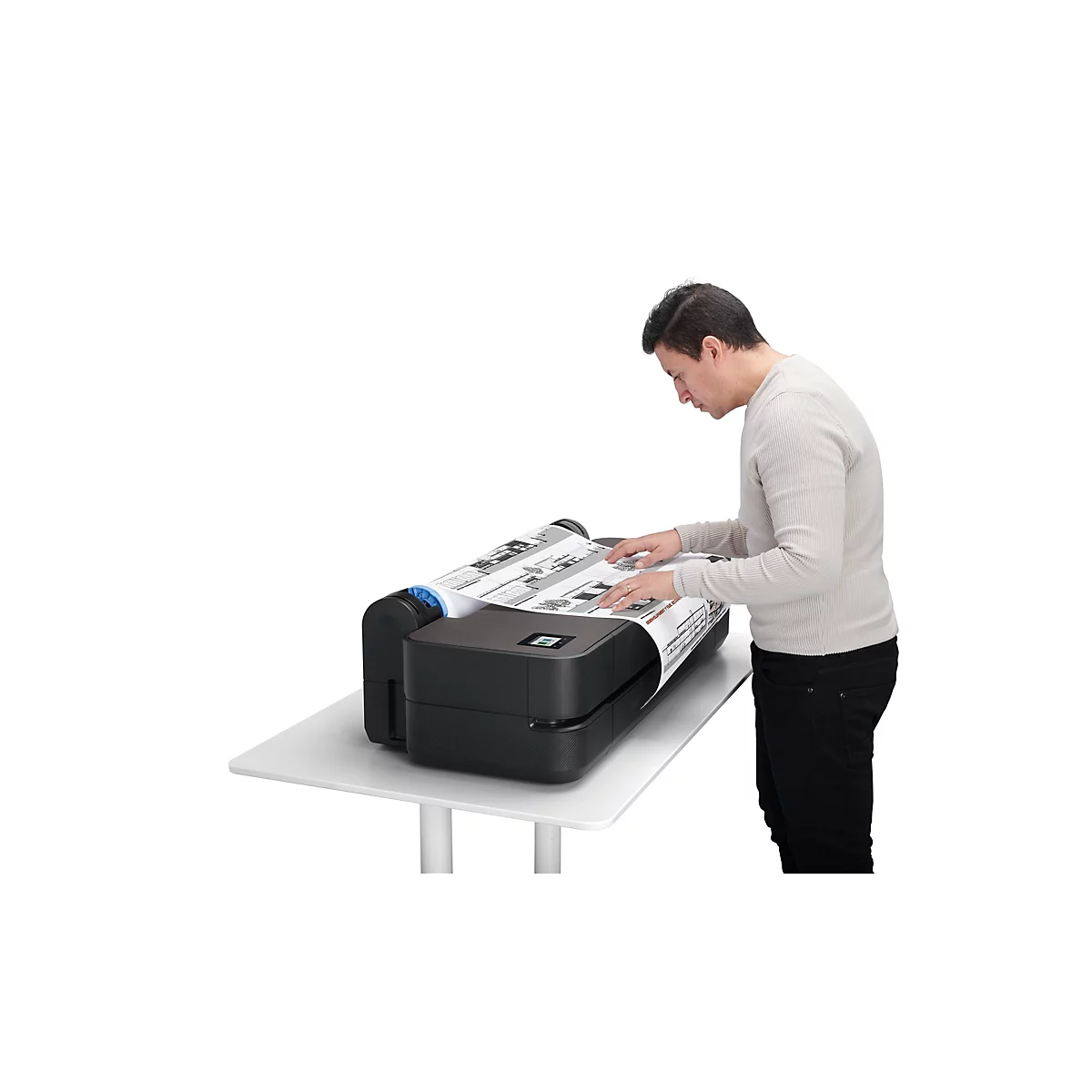 Ein Mann betrachtet Ausdrucke aus einem Großformatdrucker, der auf einem weißen Tisch steht.