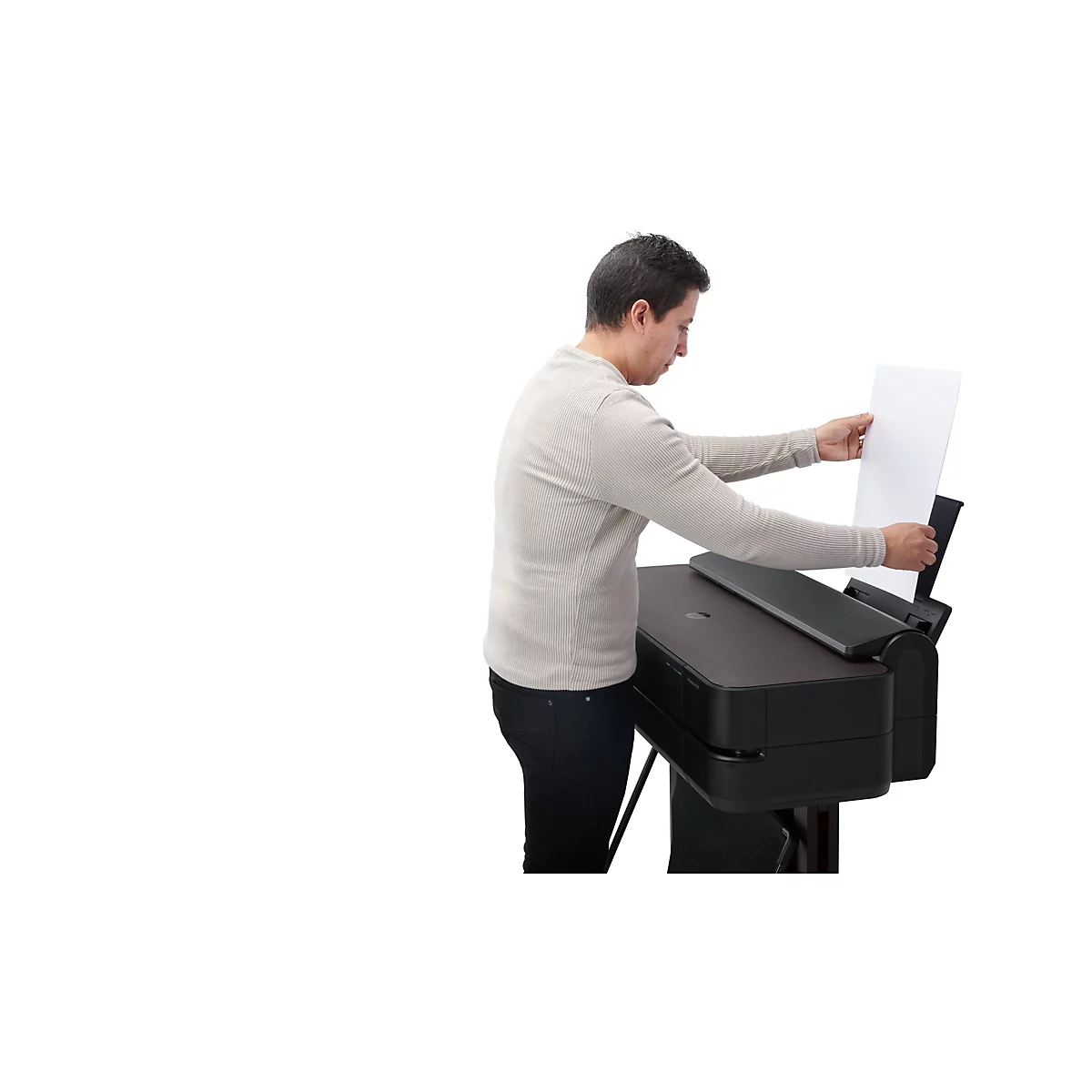 Mann legt Papier in einen Drucker ein.