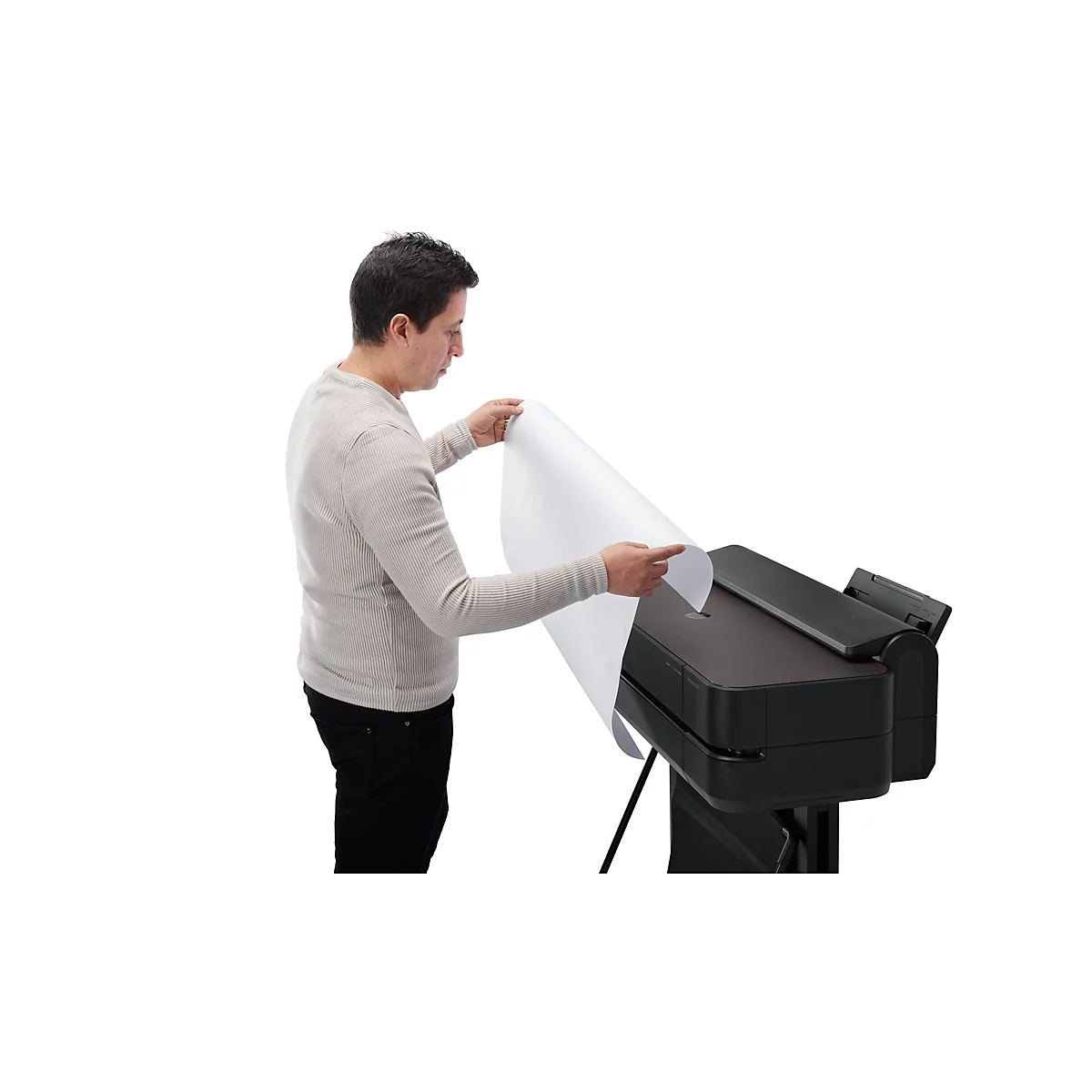 Ein Mann hält ein großes Blatt Papier, das er in einen Drucker einführt. Er steht vor einem weißen Hintergrund.