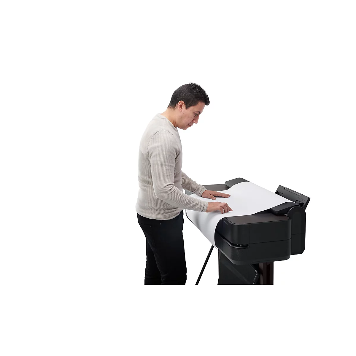 Ein Mann in beigem Pullover steht an einem grossformatigen Drucker. Er legt Papier auf die schwarze Druckoberfläche.