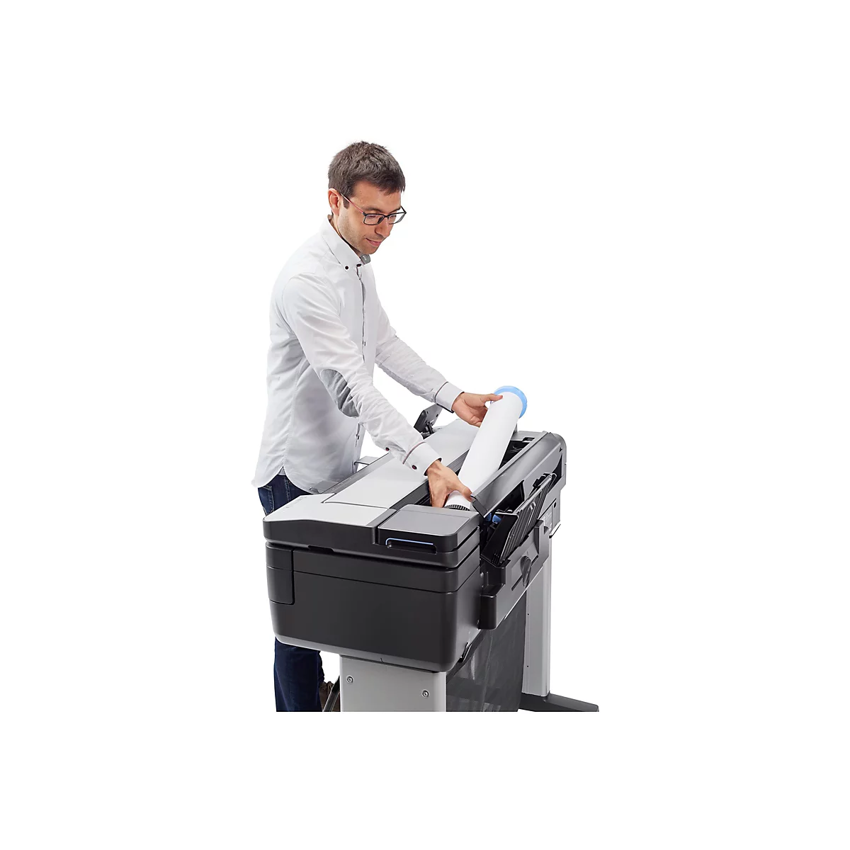 Ein Mann in Brille und Hemd legt eine Rolle Papier in einen grossen Drucker.