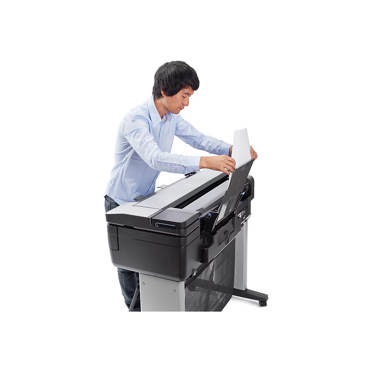 Ein Mann legt Papier in einen grossen Drucker ein. Er trÃ¤gt ein hellblaues Hemd und steht vor weissem Hintergrund.