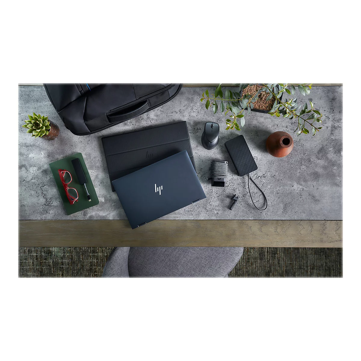Draufsicht auf einen Schreibtisch mit Notebook, ZubehÃ¶r und Pflanzen. Das Notebook trÃ¤gt das HP-Logo.