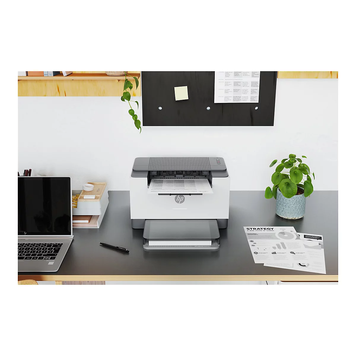 Weißer HP-Laserdrucker mit einem Blatt Papier, schwarzem Laptop und Bürozubehör auf einem Schreibtisch, Hintergrund weiß und Holz.