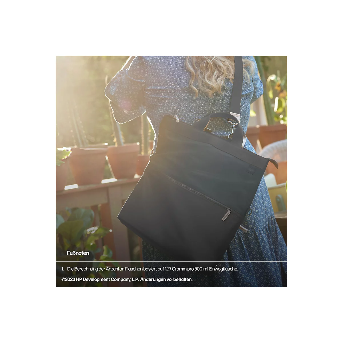 Eine Frau mit schulterlangen, blonden Haaren trägt eine schwarze Handtasche mit Schultergurt. Sie steht vor einem sonnigen Hintergrund mit Pflanzen und Blumentöpfen. Das Bild hat einen warmen, natürlichen Farbton.