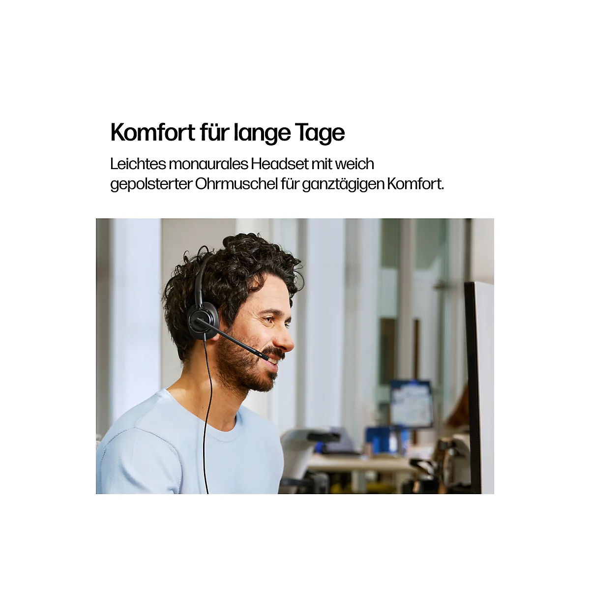 Ein Mann mit Bart trägt ein schwarzes Headset. Er lächelt und blickt nach rechts. Im Hintergrund sind weitere Bürogegenstände zu sehen.
