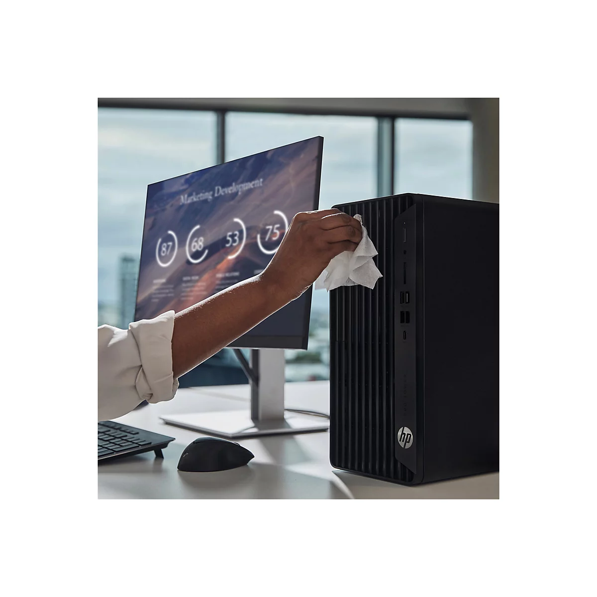 Eine Person reinigt einen schwarzen Desktop-PC. Auf dem Bildschirm sind Diagramme zu sehen.