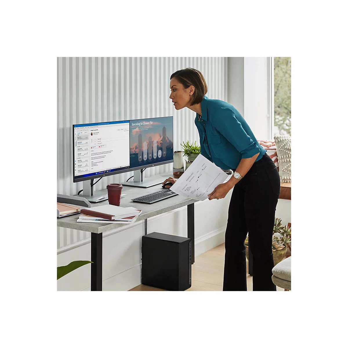 Frau arbeitet am Schreibtisch mit Computer, betrachtet Unterlagen. BÃ¼roumgebung.