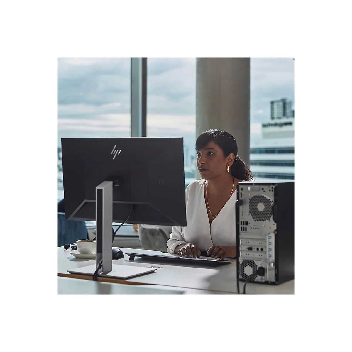 Eine Frau arbeitet am Computer im BÃ¼ro. Vorne HP Monitor, Tastatur, daneben der Tower.