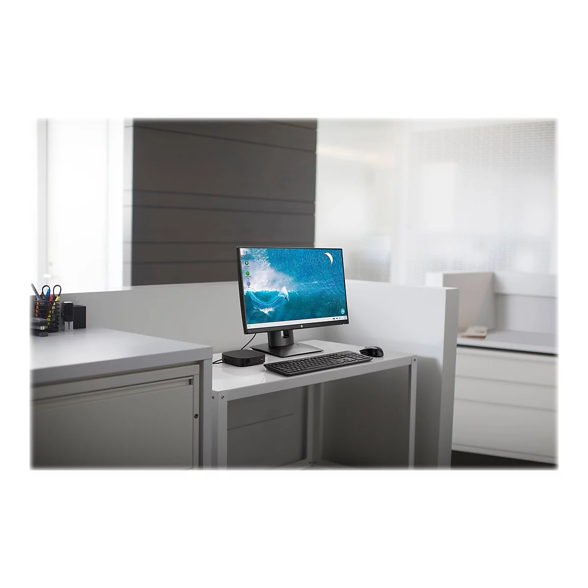 Ein Computerarbeitsplatz mit Monitor, Tastatur und Maus. Auf dem Monitor ist eine Surf-Szene zu sehen.