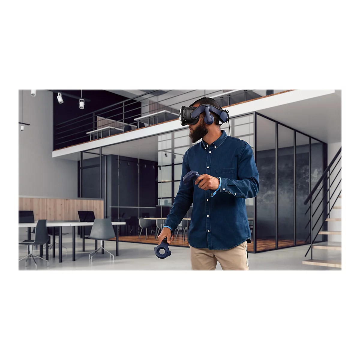 Ein Mann mit VR-Brille in einem Büro. Er hält Controller. Im Hintergrund sind weitere Büromöbel zu sehen.
