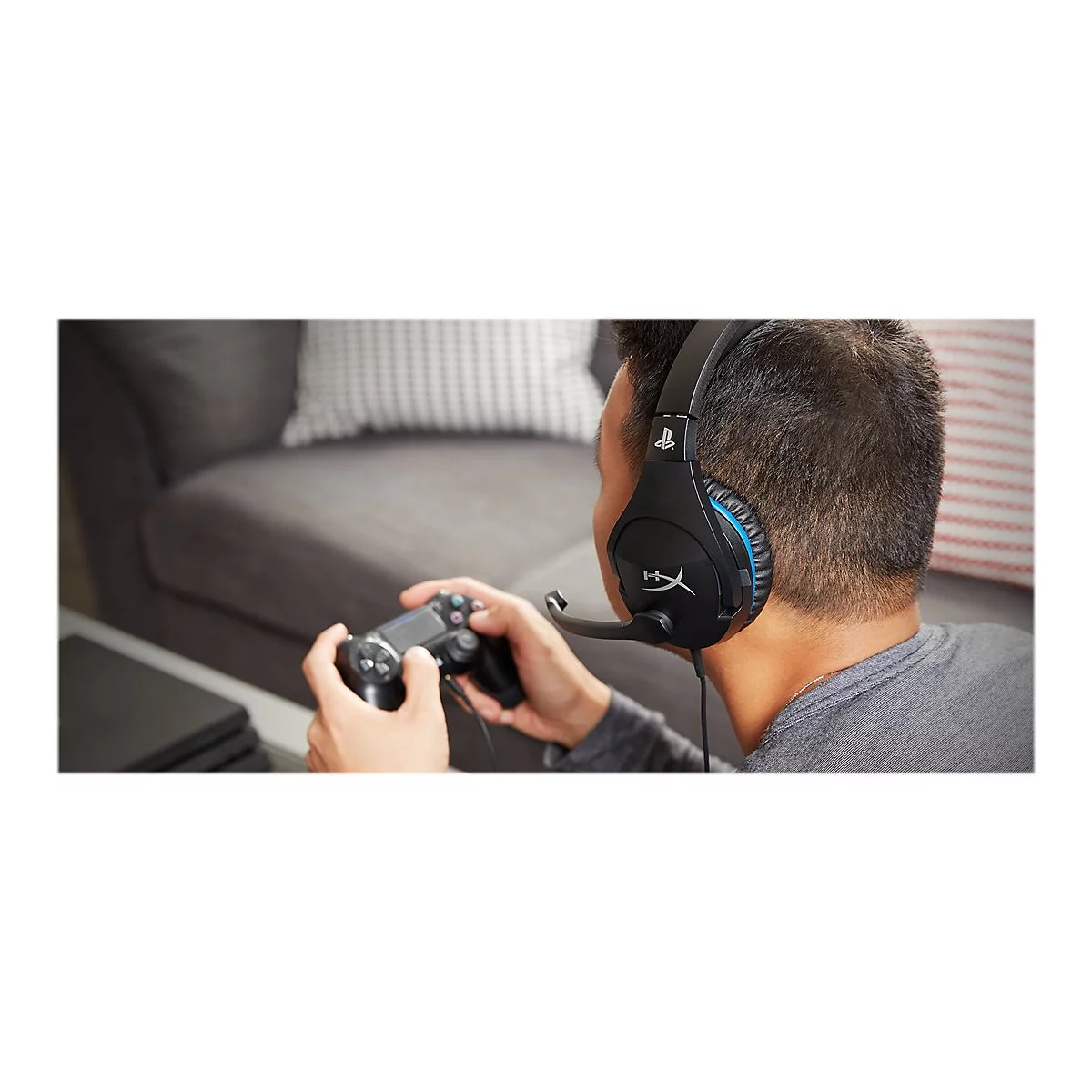 Person spielt Videospiel. Er trÃ¤gt ein Headset, hÃ¤lt Controller und sitzt auf einem Sofa.