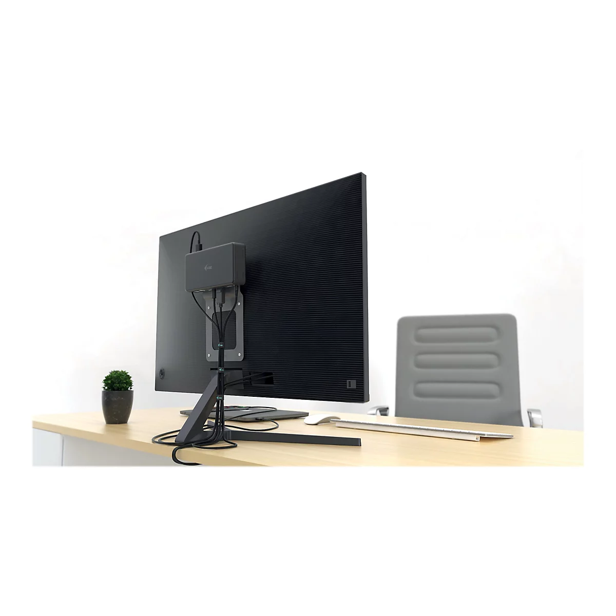 ArriÃ¨re d'un moniteur noir avec une boÃ®te montÃ©e. En dessous, un support sur la table. En arriÃ¨re-plan, une chaise de bureau.