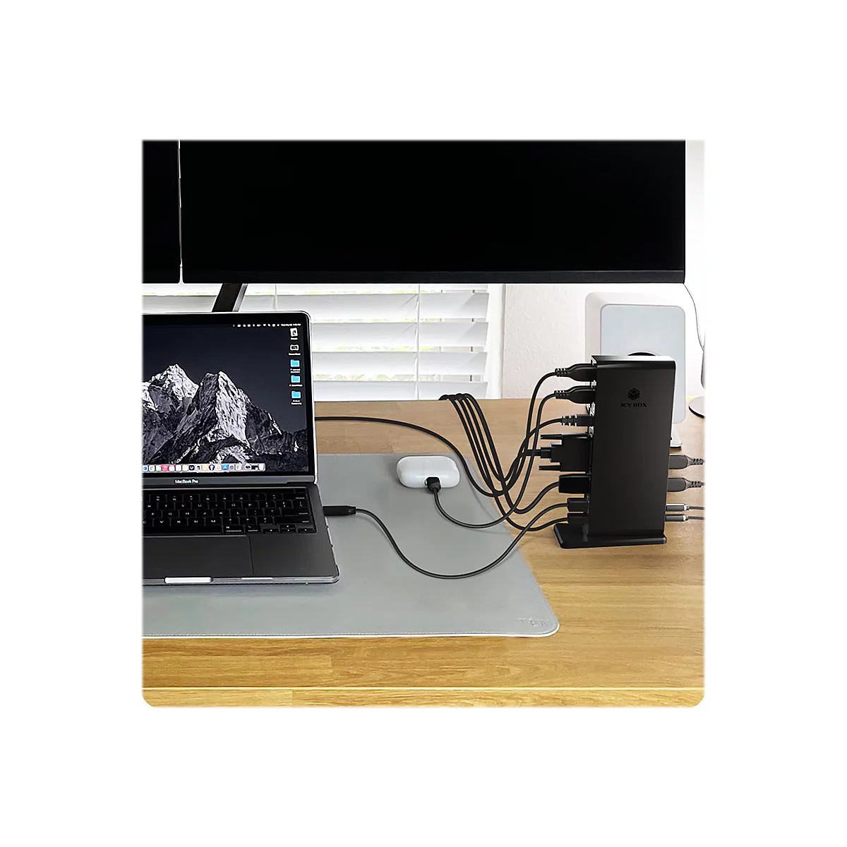 Schreibtisch mit Laptop, Monitor, USB-Hub und angeschlossenen Kabeln.