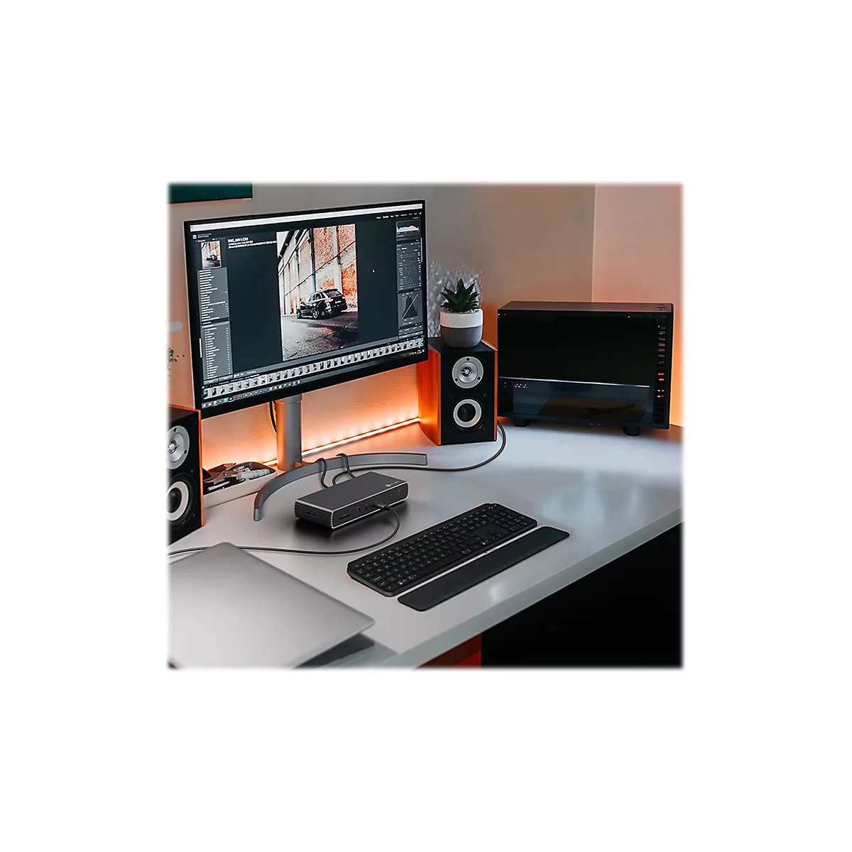 Schreibtisch mit Monitor, Lautsprechern, Tastatur und einem PC-GehÃ¤use. Auf dem Monitor wird eine Bildbearbeitungssoftware angezeigt.