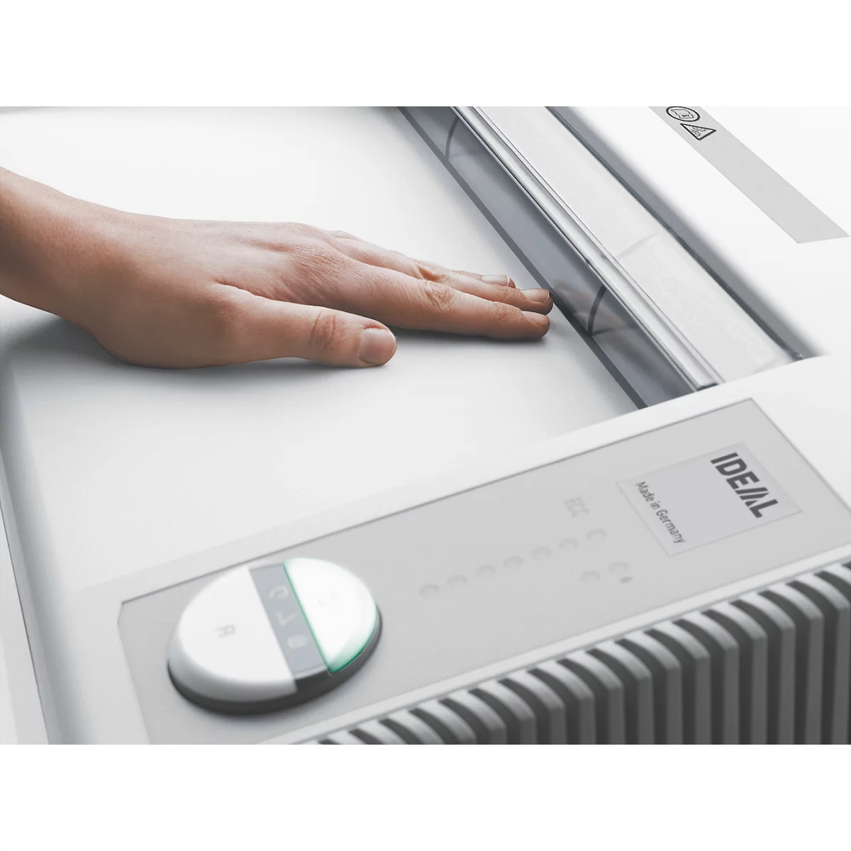 Nahaufnahme einer Hand auf einem weißen Gerät. Es gibt einen runden Knopf mit einem grünen Licht.