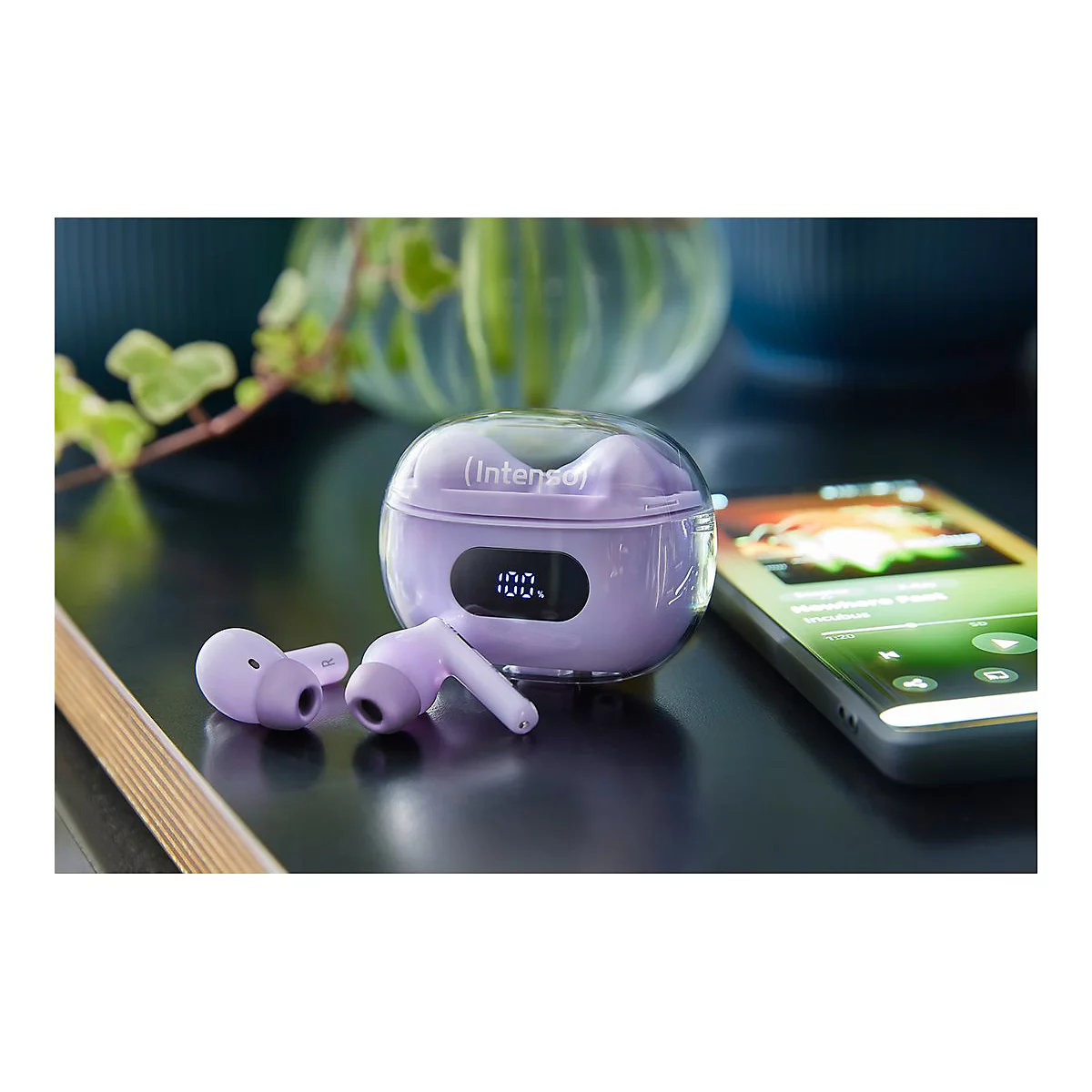 Lila Intenso In-Ear-Kopfhörer mit Ladecase und Digitalanzeige neben einem Smartphone auf einem Tisch.