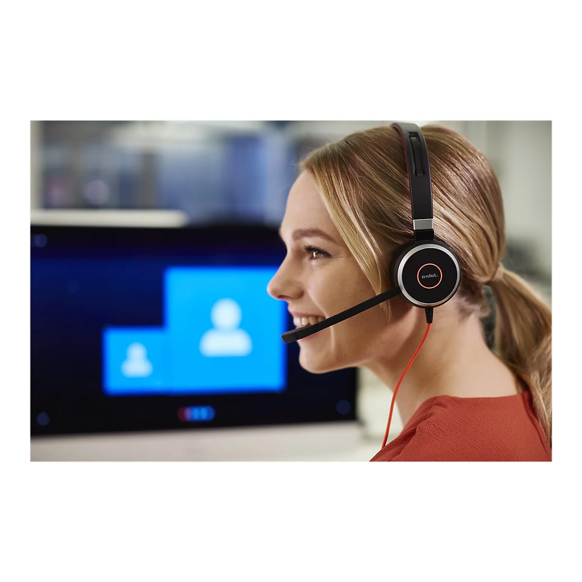 Eine lÃ¤chelnde Frau mit blonden Haaren trÃ¤gt ein Headset. Im Hintergrund ein Bildschirm mit blauen Elementen.
