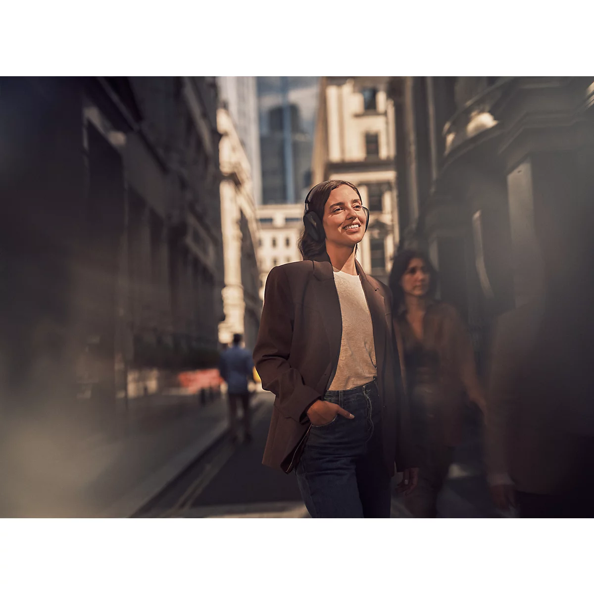 Femme souriante avec un casque marchant dans une rue animée.