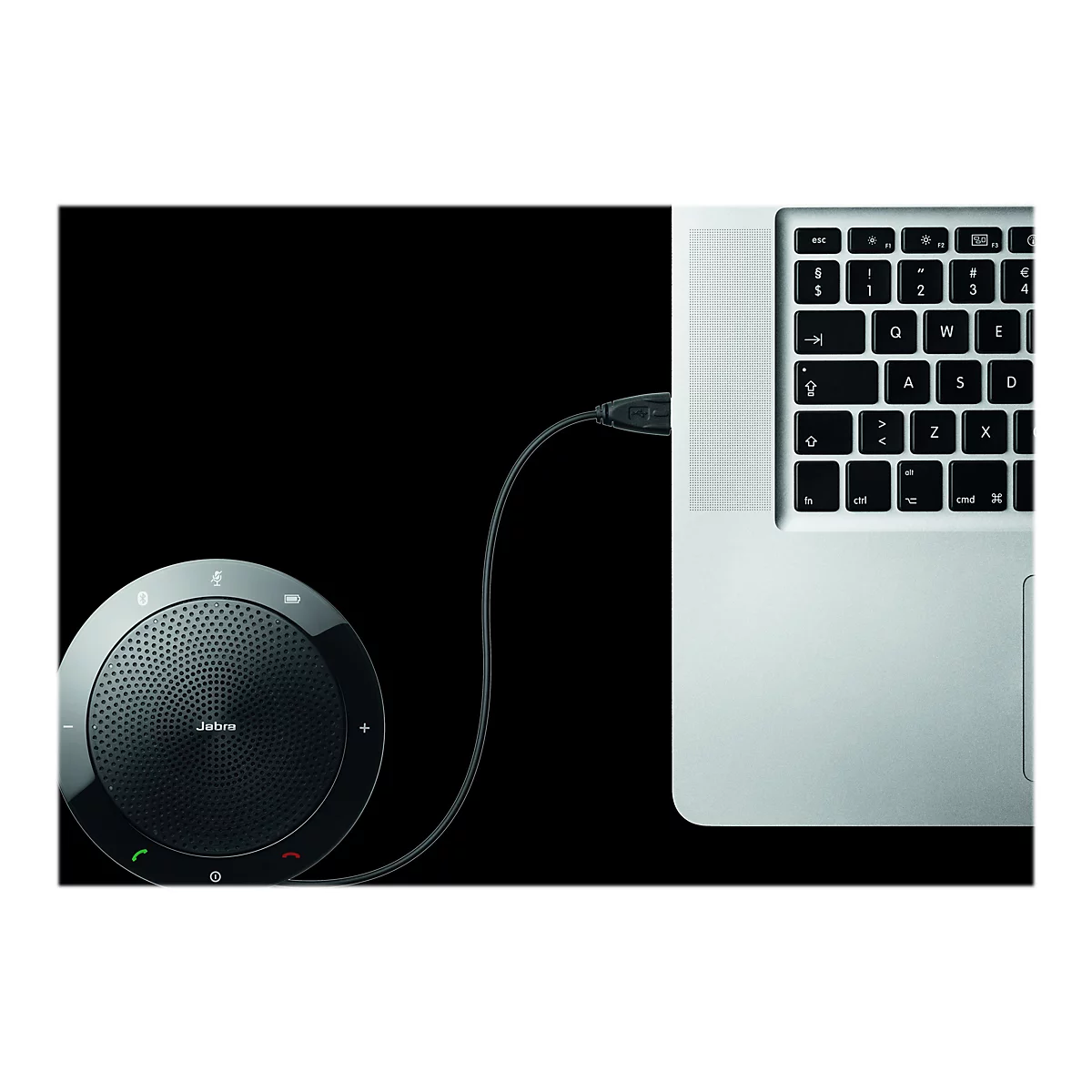 Ein schwarzes Jabra-Lautsprecherphone, das über ein USB-Kabel an einen Laptop angeschlossen ist. Die Tastatur ist teilweise zu sehen.