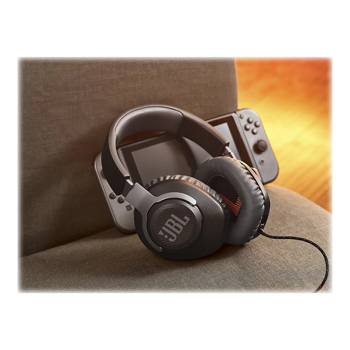 Schwarzer JBL-Kopfhörer liegt auf einem grauen Stuhl. Dahinter ist eine Nintendo Switch.