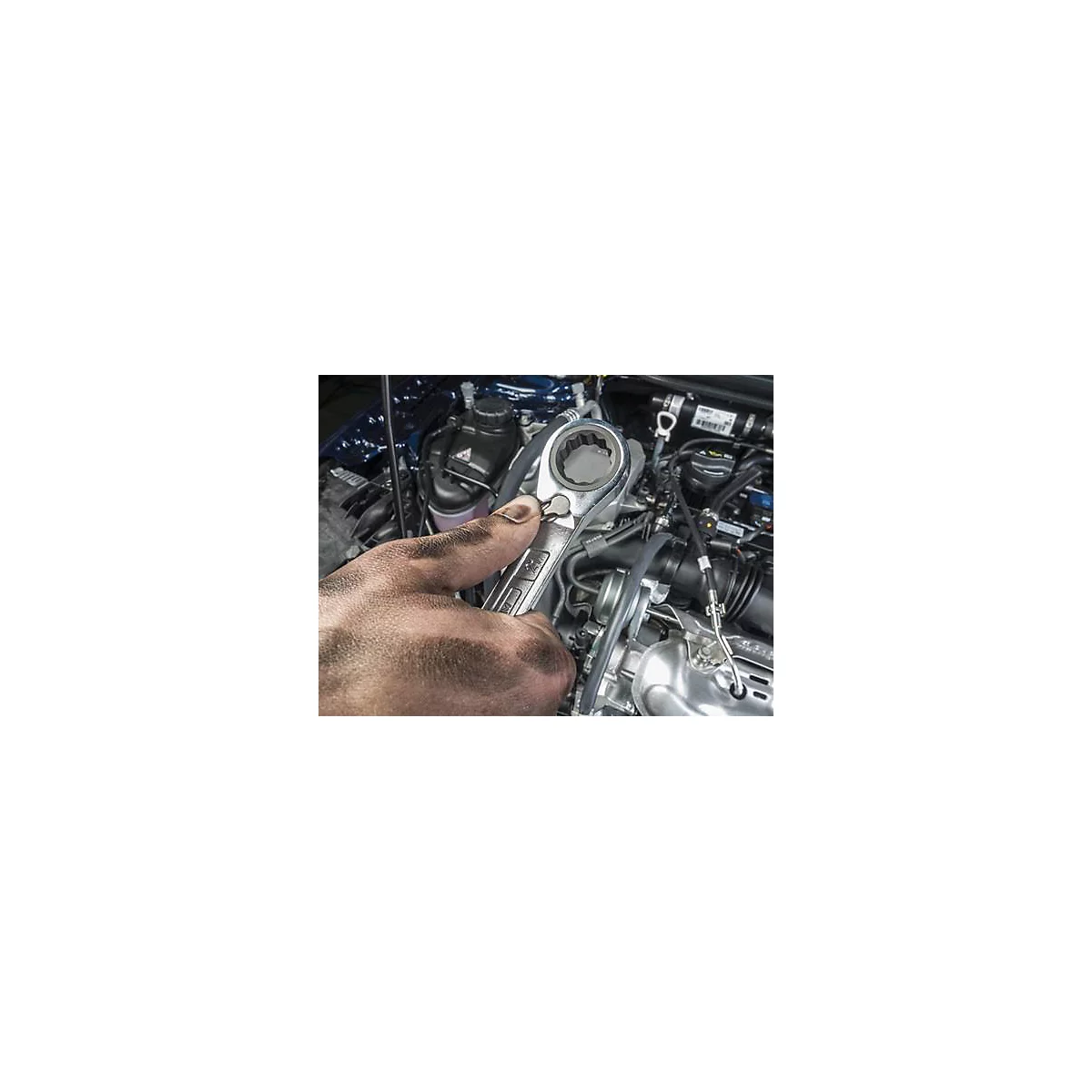 Main sale tenant une clé sur un moteur de voiture. Détails : métal, moteur, outil.