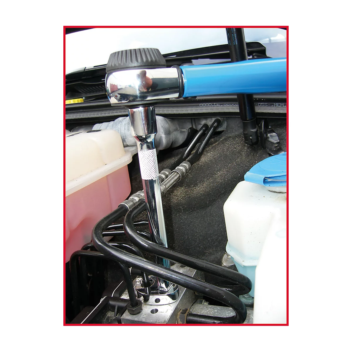 Vue à l'intérieur d'un compartiment moteur. Un outil est utilisé pour travailler sur des tuyaux.