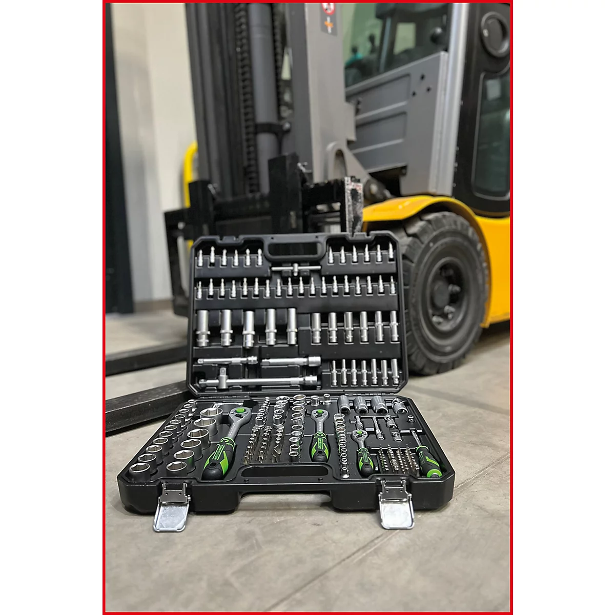 Mallette à outils ouverte avec douilles et cliquets devant un chariot élévateur jaune.