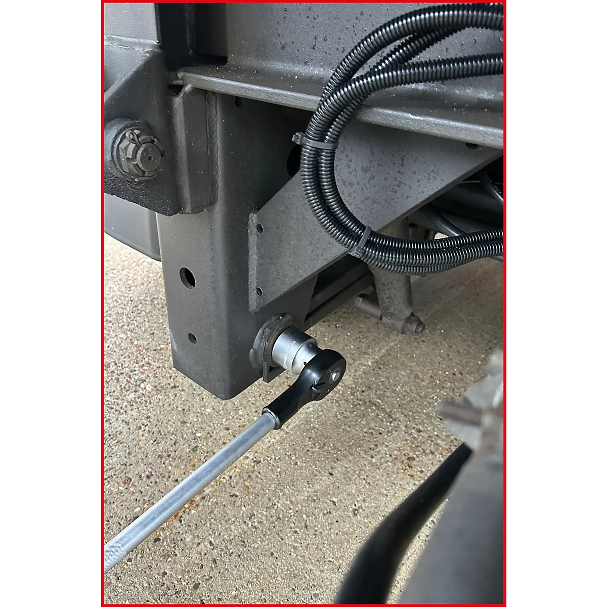 Gros plan sur une connexion à clé à cliquet sur un cadre métallique gris.