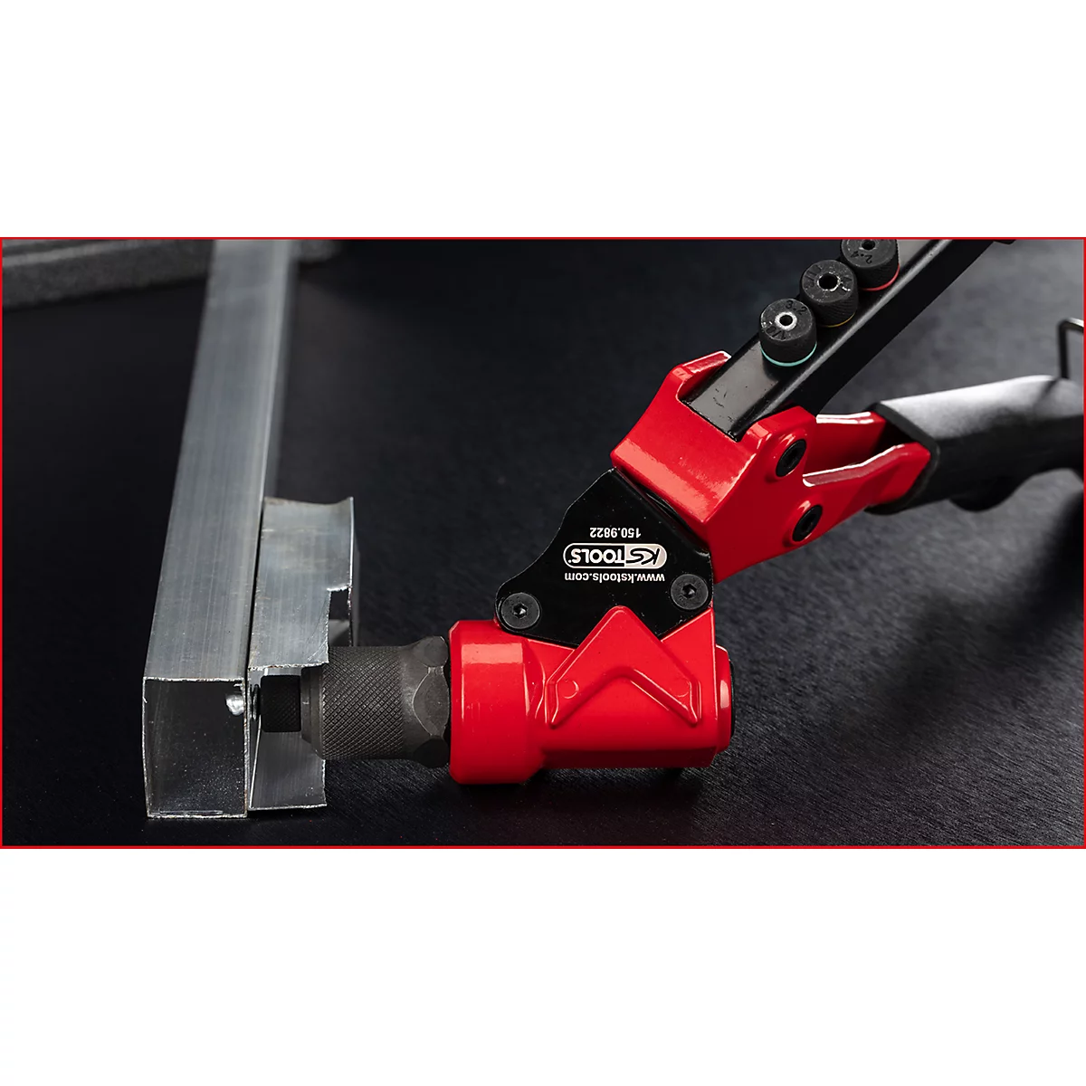 Pince à poinçonner rouge KS Tools utilisée sur un profilé métallique.