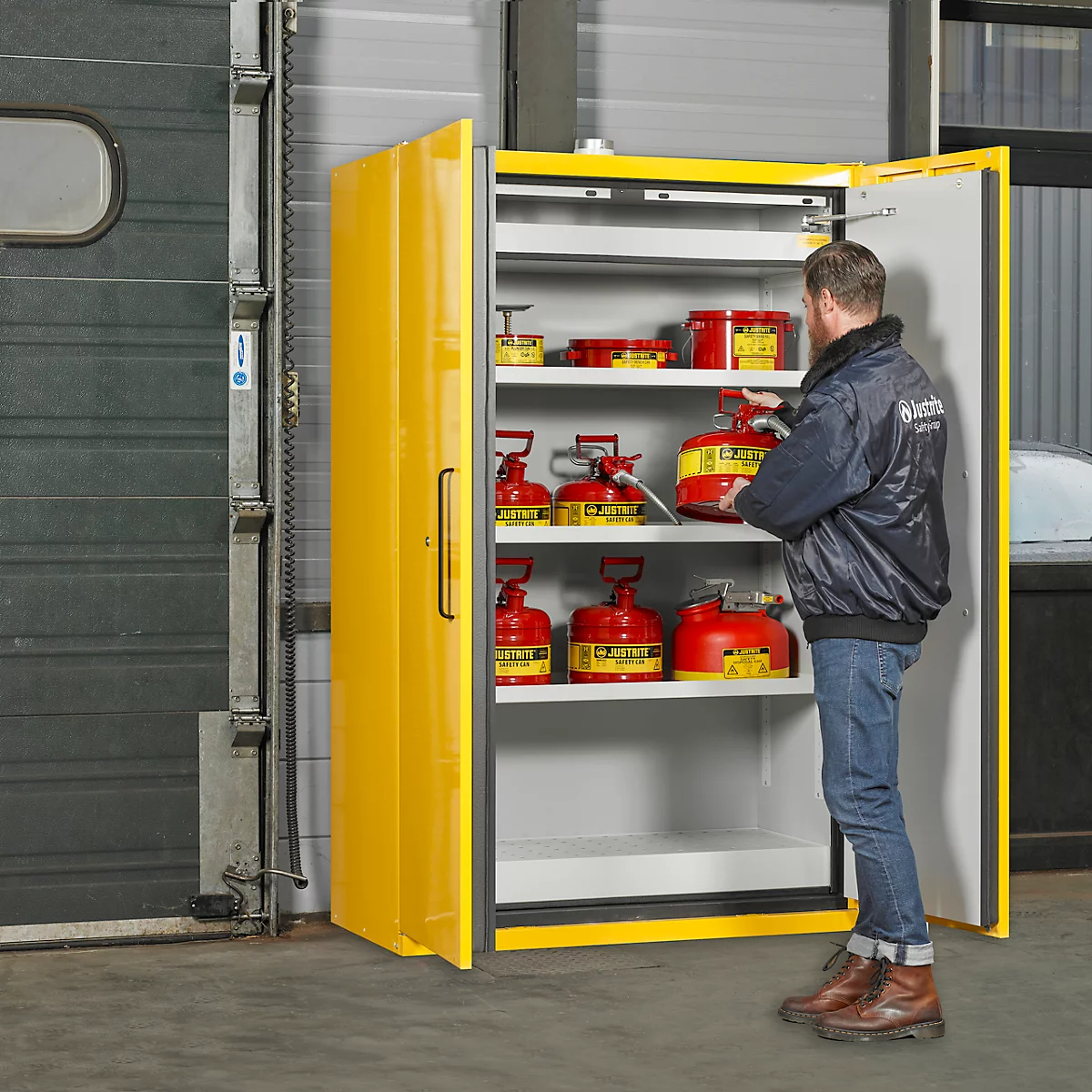 Un homme se tient près d'une armoire jaune. L'armoire contient des bidons rouges. Il sort un bidon de l'armoire.