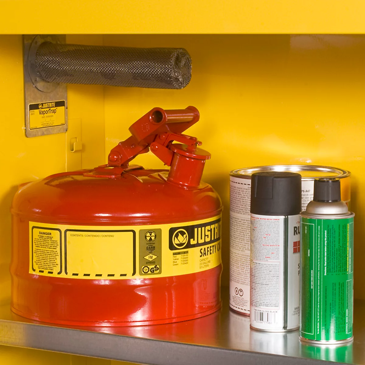Bidon d'essence rouge et sprays dans une armoire jaune. Impression 'JUSTR SAFETY'.