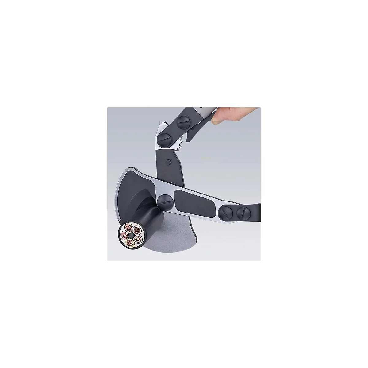 Kabelkniptang snijdt kabel. De koperdraden zijn zichtbaar. Een arm houdt het gereedschap vast.