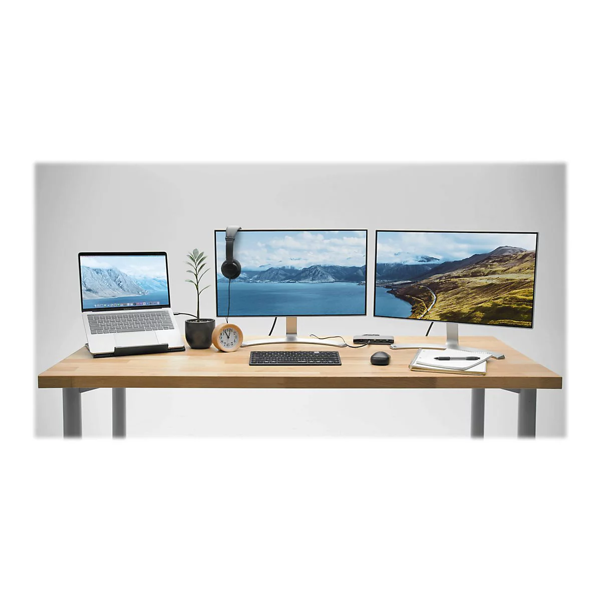 Une configuration de bureau avec un ordinateur portable, deux moniteurs, un casque et des accessoires sur fond blanc.